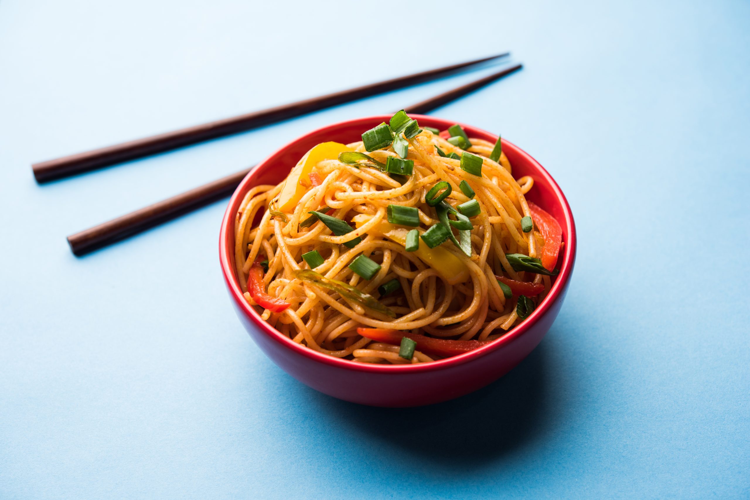 Schezwan Noodles or vegetable Hakka Noodles or chow mein is a popular Indo-Chinese recipes, served in a bowl or plate with wooden chopsticks. selective focus Schezwan Noodles or vegetable Hakka Noodles or chow mein is a popular Indo-Chinese recipes, served in a bowl or plate with wooden chopsticks. selective focus